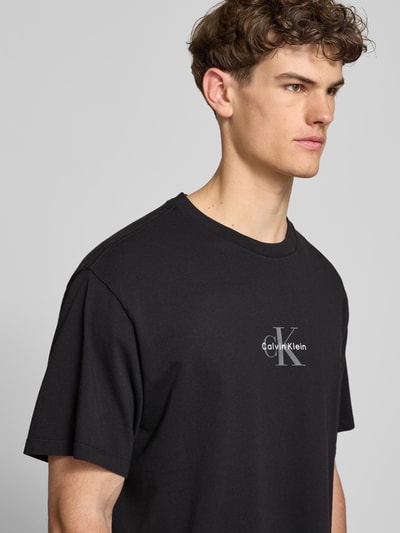 Männermodel trägt Relaxed Fit T-Shirt aus reiner Baumwolle von Calvin Klein Jeans, Optik: Unifarben, Label-Print, Nahaufnahme Oberkörper.