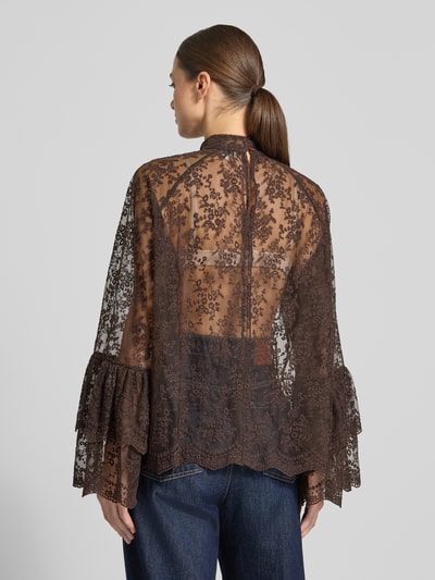 Modelka kobieca ma na sobie Blusenshirt aus Spitze mit Stehkragen od Milano Italy z mieszanki bawełny, półprzezroczysty materiał, stójka, krój relaxed fit, długość tyłu 66 cm, długość rękawów 64 cm, brązowa koronka, widoczne detale kwiatowe, tekstura delikatna, widok całej sylwetki od tyłu.