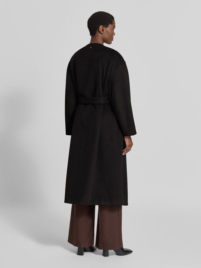 Frauenmodel trägt Mantel mit Rundhalsausschnitt und Bindegürtel von Armani Exchange in Schwarz, A-Linie, Material-Mix mit Viskose-Anteil, Bindegürtel, braune Hose, Ganzkörperansicht Rückansicht.