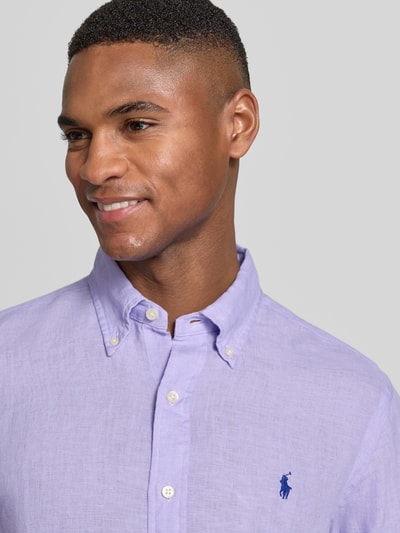 Mannelijk model draagt Regular Fit Vrijetijdsoverhemd uit puur linnen van Polo Ralph Lauren in effen lila met logodetail, nahaufnahme bovenlichaam.