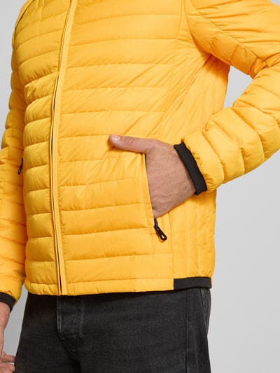 Männermodel trägt Regular Fit Jacke in Stepp-Optik Modell 'OLYMPUS' von NAUTGÅRD, gelb, sichtbarer Reißverschluss, Nahaufnahme Oberkörper. Rückenlänge 69 cm, Schulterbreite 48 cm, Brustweite 48 cm, Ärmellänge 67 cm.