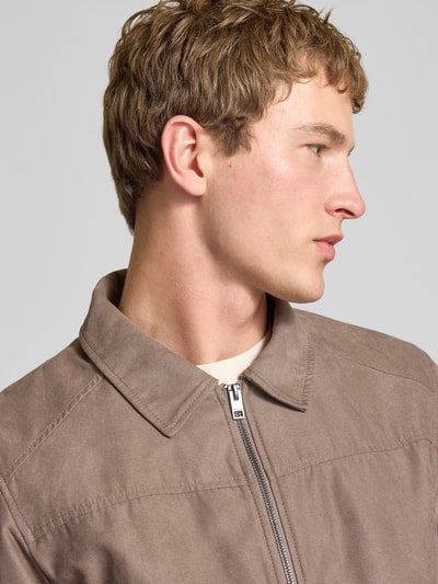 Męski model nosi Jacke mit Umlegekragen Modell 'DYLAN' od Jack & Jones, krój regular fit, zamek, brązowy kolor, zbliżenie górnej części.