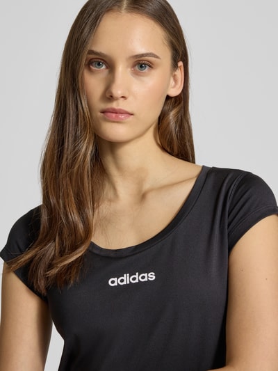 Frauenmodel trägt Cropped T-Shirt mit Label-Print von adidas Sportswear aus Material-Mix mit Stretch-Anteil, Schwarz, Nahaufnahme Oberkörper.