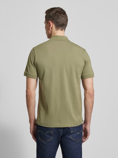 Männermodel trägt Regular Fit Poloshirt aus Baumwoll-Mix von Lacoste, unifarben, Logo-Detail, Piqué-Textur, Ganzkörperansicht Rückansicht.