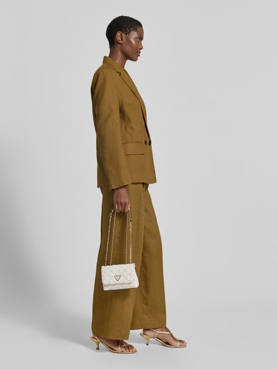 Vrouwenmodel draagt handtas met labelapplicatie model 'GIULLY II' van guess, doorgestikte naden, draagband, zijaanzicht, ganzekörperansicht van voren. Hoofdvak met overslag, breedte 17 cm, lengte 12 cm, diepte 6 cm, schouderbandlengte 124 cm.