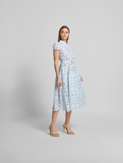 Frauenmodel trägt Midikleid aus floraler Spitze von Self-Portrait in Hellblau, taillierte Passform, Stehkragen, blickdichtes Unterkleid, kurzärmelig, zarte Textur, Gesamtlänge 118 cm, Brustweite 38 cm, Taillenweite 36 cm, Ärmellänge 13 cm, Ganzkörperansicht von vorne.