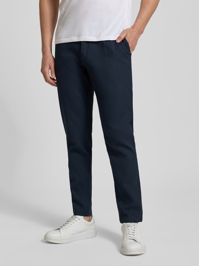 Männermodel trägt Tapered Fit Chino aus Baumwoll-Mix Modell 'CHINO PLEATED' von BOSS Orange, dunkelblau, Twill-Struktur, Ganzkörperansicht von vorne.
