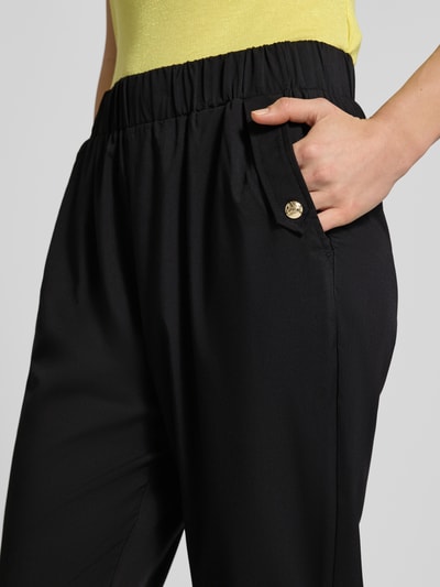Frauenmodel trägt Straight Fit Stoffhose mit Viskose-Anteil von LIU JO SPORT, Material-Mix, elastischer Bund, Zierbesatz, Nahaufnahme Oberkörper.