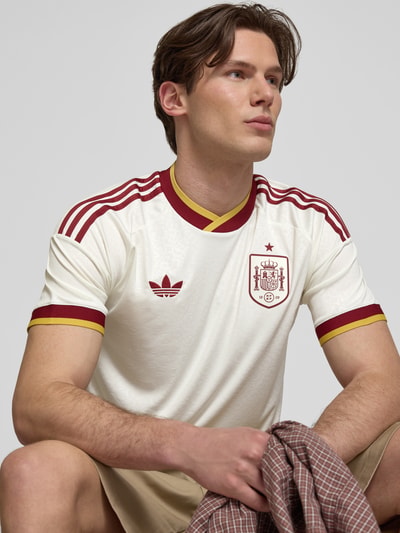 Männermodel trägt Spanje Auswärtstrikot 2026 van adidas Sportswear in meerkleurig look met regular fit, logo-applicatie, contraststrepen, gestikt logo, ronde hals, korte mouw en climacool technologie. Nahaufnahme Oberkörper.