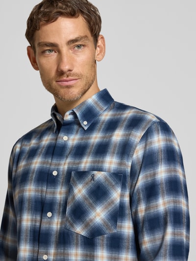 Mężczyzna nosi Relaxed Fit Freizeithemd aus reiner Baumwolle Modell 'COTTON CHECK LONGSLEEVE' von ARMEDANGELS, odcienie niebieskiego i beżu, kratka, tekstura miękka, koszula casualowa, Nahaufnahme Oberkörper.