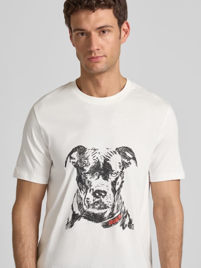 Männermodel trägt Regular Fit T-Shirt aus reiner Baumwolle Modell 'DUBROX' von HUGO, unifarben, Motiv-Print, Nahaufnahme Oberkörper.