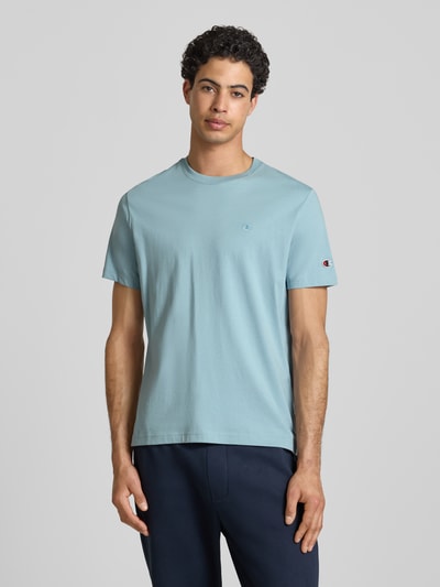 Männermodel trägt T-shirt met labelstitchings en ronde hals van CHAMPION in lichtblauw, puur katoen, regular fit, ruglengte maat M 66 cm, Ganzkörperansicht van voren.