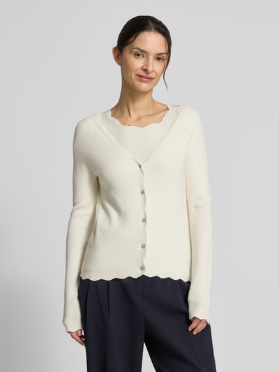 Frauenmodel trägt Strickcardigan aus Viskose-Mix von Christian Berg Woman in Offwhite mit Rüschen, Knopfleiste, V-Ausschnitt, Nahaufnahme Oberkörper.
