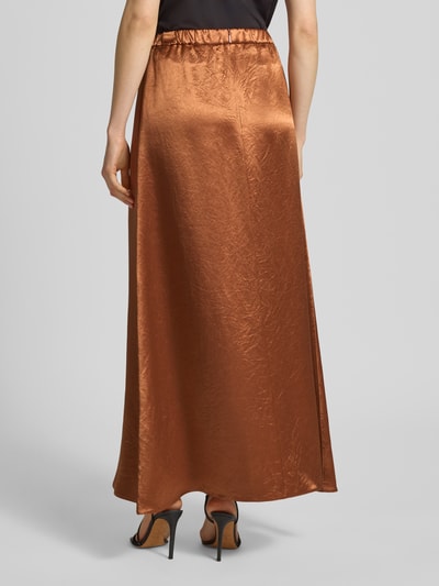 Kobiece modelka nosi długą spódnicę z satyny z elastycznym pasem model 'TUONO' od MM by Max Mara, linia a, kolor miedziany, całkowita długość 106 cm, szerokość w rozmiarze 36: 37 cm, widok całej sylwetki z tyłu.