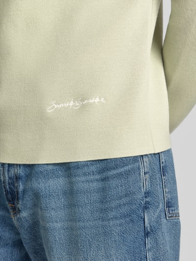 Mężczyznę model nosi sweter z mieszanki wiskozy z dodatkiem streczu z wyhaftowanym logo, model 'MATT' od Samsøe Samsøe, krój slim fit, okrągły dekolt, długość tyłu w rozmiarze M: 67 cm, długość rękawa w rozmiarze M: 68 cm, jasny odcień, gładka struktura, detal z przodu, zdjęcie w zbliżeniu na dolną część pleców
