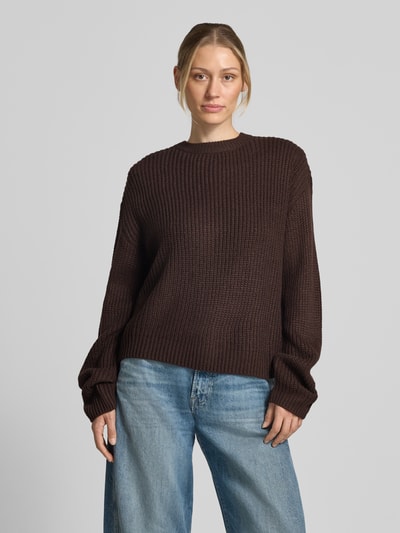 Frauenmodel trägt Regular Fit Pullover mit Crew Neck Modell 'LEA' von VERO MODA in Dunkelbraun mit grober Strickstruktur, Ganzkörperansicht von vorne.