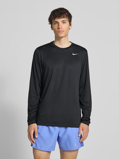 Mężczyzna model nosi bluzkę z długim rękawem z nadrukiem z logo i okrągłym dekoltem od NIKE TRAINING, krój straight fit, jednokolorowy design, długość tyłu w rozmiarze M: 70 cm, całkowity widok z przodu