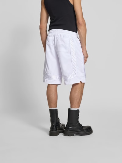 Männermodel trägt Shorts mit elastischem Bund von RHUDE in Weiß mit Mesh, Eingrifftaschen, lockerer Passform, Ganzkörperansicht Rückansicht.