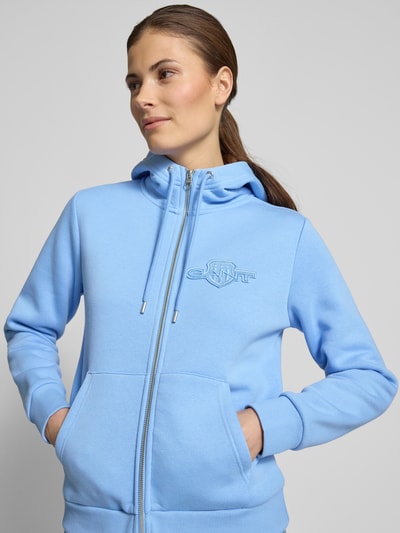 Frauenmodel trägt Sweatjacke mit Zweiwege-Reißverschluss und Label-Stitching von Gant, hellblau, Baumwoll-Mix, Känguru-Tasche, Nahaufnahme Oberkörper
