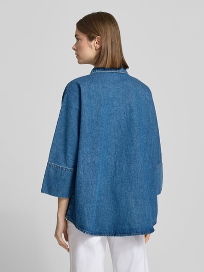 Vrouwenmodel draagt Loose Fit jeansblouse uit puur katoen model 'GRACE' van Only in denimlook met overhemdkraag, drukknoopsluiting, 3/4-kimonomouwen, damesmode, context: pasvorm loose fit, overslag schouders, detailopname rugaanzicht.