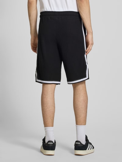 Männermodel trägt Shorts mit Logo-Stitching Modell 'Signar' von Pegador aus Reine Baumwolle, Gerader-Schnitt, Kontraststreifen, Ganzkörperansicht Rückansicht.