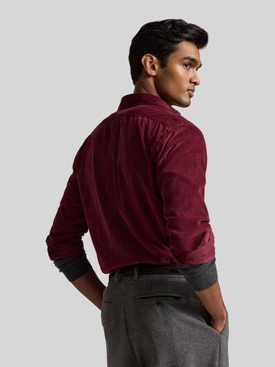 Männermodel trägt Custom Fit Freizeithemd aus reiner Baumwolle von Polo Ralph Lauren in Dunkelrot, graue Hose, Ganzkörperansicht Rückansicht.
