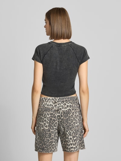 Frauenmodel trägt Slim Fit Crop Top aus Baumwoll-Mix Modell 'ribbed baby' von TRUE RELIGION in Schwarz, kombiniert mit Leo-Shorts, Ganzkörperansicht Rückansicht.