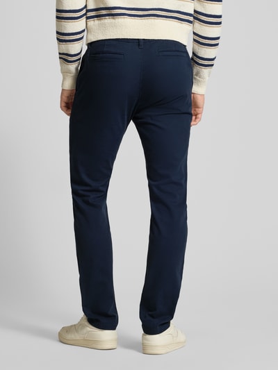 Männermodel trägt Schmale Chino mit gerader Silhouette und mittlerer Bundhöhe von REVIEW in Dunkelblau, Gesäßtaschen, Ganzkörperansicht Rückansicht. Baumwoll-Elasthan-Mix, Slim Fit, mittlere Bundhöhe, Bundweite M: 43 cm, Innenbeinlänge M: 81 cm.