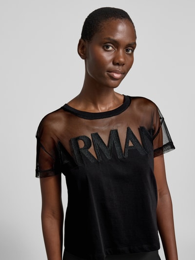 Frauenmodel trägt Regular Fit T-Shirt mit Logo-Stitching von ARMANI EXCHANGE, schwarze reine Baumwolle, semitransparent, Nahaufnahme Oberkörper.