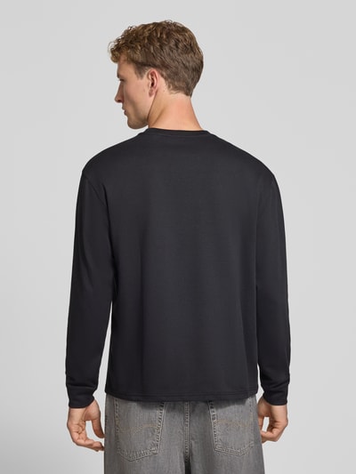 Männermodel trägt schwarzes Relaxed Fit Langarmshirt aus Baumwoll-Mix Modell 'SCASPIAN' von ONLY, Herren T-Shirt, Ganzkörperansicht Rückansicht.