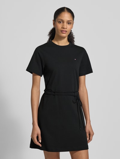Vrouwenmodel draagt Tailliertes Sweatkleid aus reiner Baumwolle van Tommy Hilfiger, zwart, uni, taillering fit, mini, rond hals, logo-stiksel, zonder sluiting, bindriem, korte mouw, rechte zoom, interlock, puur katoen, volledige lichaamsopname van voren.