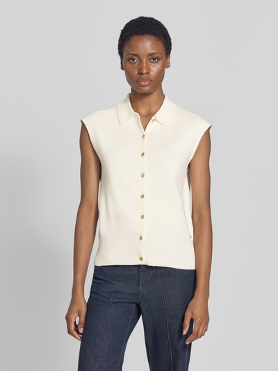 Frauenmodel trägt Relaxed Fit Weste aus Baumwoll-Mix von Tommy Hilfiger in Creme mit goldfarbenen Knöpfen, kombiniert mit Jeans, Ganzkörperansicht von vorne. Damen Weste von Tommy Hilfiger.