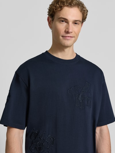 Männermodel trägt T-Shirt mit Stitchings und Rundhalsausschnitt von Scotch & Soda in Dunkelblau, reine Baumwolle, Relaxed Fit, Nahaufnahme Oberkörper