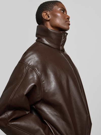 Frauenmodel trägt Oversized Jacke mit Leder-Anteil von Anine Bing in Braun mit Stehkragen, Material-Mix, Nahaufnahme Oberkörper. Rückenlänge 61 cm, Brustweite 64 cm, Ärmellänge 56 cm, gefütterter Stehkragen, durchgehender Verschluss mit Abdeckleiste, überschnittene Schultern.