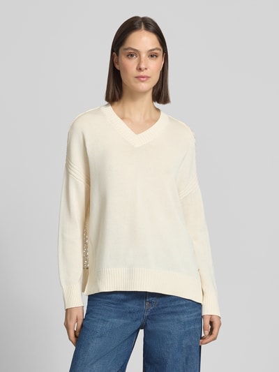 Frauenmodel trägt Strickpullover mit V-Ausschnitt von ARMANI EXCHANGE, cremefarben, relaxed Fit, reine Baumwolle, Ganzkörperansicht von vorne.