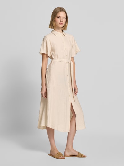 Frauenmodel trägt Midikleid aus Viskose-Mix mit Umlegekragen von COMMA in Beige mit Knopfleiste und Taillienband, Ganzkörperansicht von vorne.