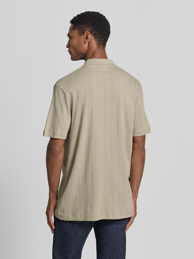 Männermodel trägt Regular Fit Poloshirt mit kurzer Knopfleiste von Lindbergh aus Reine Baumwolle mit Jaquard-Strick, Rückenlänge 70 cm, Ganzkörperansicht Rückansicht.