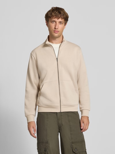 Männermodel trägt Regular Fit Sweatjacke mit Baumwoll-Anteil Modell 'Bradley' von JACK & JONES in Beige, Kängurutasche, Ganzkörperansicht von vorne.