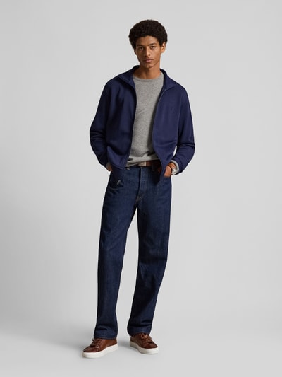 Männermodel trägt Relaxed Fit Sweatjacke aus Baumwoll-Mix von Polo Ralph Lauren in Dunkelblau, kombiniert mit Jeans, Ganzkörperansicht von vorne.
