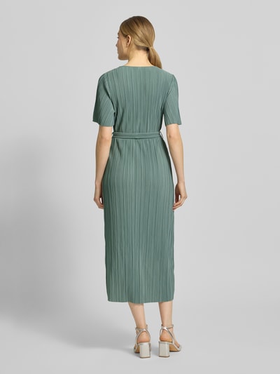 Frauenmodel trägt Cocktailkleid in Wickel-Optik Modell 'LINDA' von YAS in Grün, feine Plissee-Struktur, tailliert, Midilänge, Ganzkörperansicht Rückansicht