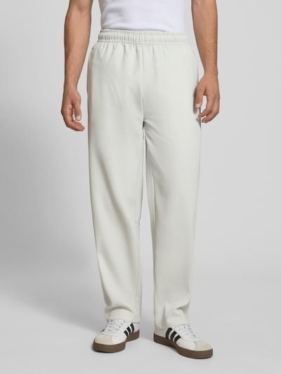 Mężczyzna nosi Sweatpants mit Strukturmuster und elastischem Bund von Pegador, jasny kolor, materiał z fakturą, relaxed fit, widok z przodu, zdjęcie całej sylwetki.