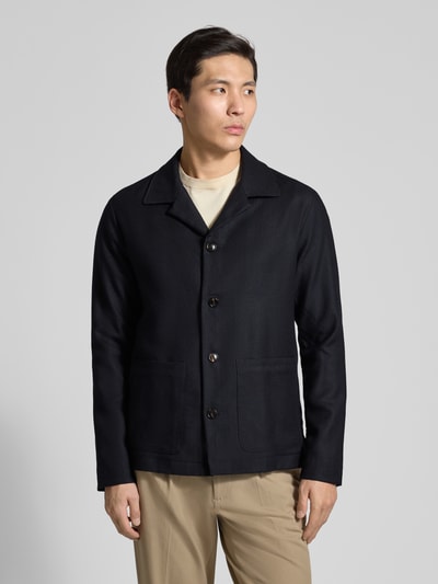 Męski model nosi Regular Fit Hemdjacke aus Schurwolle mit Reverskragen od Profuomo, czysta żywa wełna, krój regular fit, kołnierz z połami, listwa guzikowa, nakładane kieszenie, długość tyłu w rozmiarze M: 74 cm, kolor czarny, gładka tekstura, widok całej sylwetki z przodu