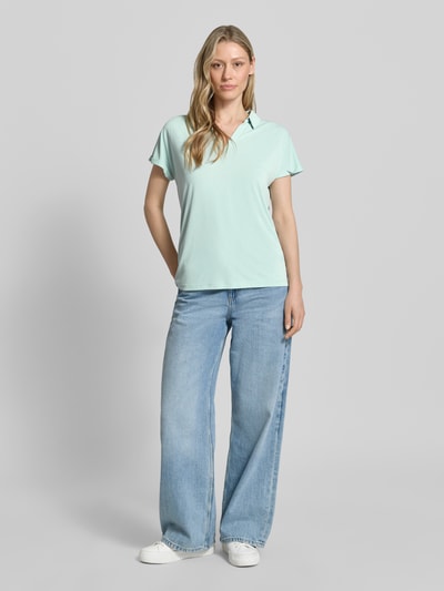 Frauenmodel trägt Regular Fit Poloshirt aus Modal-Mix von Christian Berg Woman in Mint mit V-Ausschnitt und Aufschlag an den Ärmeln, Ganzkörperansicht von vorne. Rückenlänge bei Größe S: 46 cm.