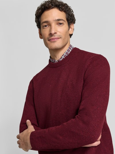 Männermodel trägt Pullover aus Woll-Seide-Mix mit Rundhalsausschnitt Modell 'TISBURY' von BARBOUR in Rot, Stricktextur, Nahaufnahme Oberkörper.