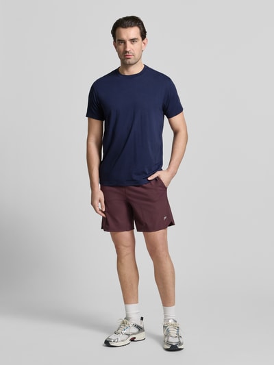 Męski model nosi Regular Fit T-Shirt mit Rundhalsausschnitt od Fabletics, bawełniany miks z modalem, kolor granatowy, krótki rękaw, krój regular fit. Widok całej sylwetki z przodu.