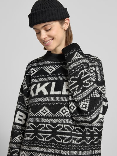 Frauenmodel trägt Jacquard-Strickpullover mit Rundhalsausschnitt von Karo Kauer in Schwarz-Weiß mit Relaxed Fit und Label-Detail, Nahaufnahme Oberkörper.