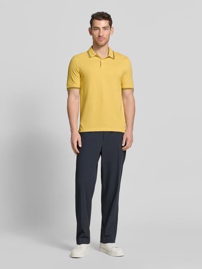 Männermodel trägt Regular Fit Poloshirt mit Logo-Stitching von bugatti in Gelb, Reine Baumwolle, Polokragen, kurze Knopfleiste, Label-Detail, Ganzkörperansicht von vorne.