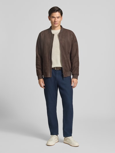 Männermodel trägt Slim Fit Strickpullover aus reiner Wolle mit Label-Stitching von MCNEAL, helle Farbe, Ganzkörperansicht von vorne.