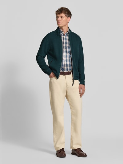 Męski model nosi Regular Fit Jacke aus Baumwoll-Mix Modell 'SELANIK' od LERROS, kolor głęboka zieleń, gładka tekstura, zamek, kieszenie, długość tyłu w rozmiarze M: 69 cm, długość rękawa: 65 cm, pełen widok z przodu.