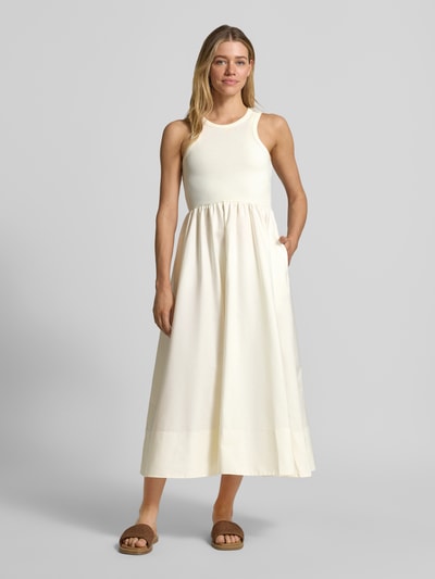 Vrouwenmodel draagt midi-jurk met ronde hals model 'MIRI' van YAS, mix van katoen en elastaan, a-lijn, ruglengte maat S 125 cm, borstwijdte 37 cm, kleuren crème en lichtgeel, structuur glad, geheel lichaamsaanzicht voorkant.